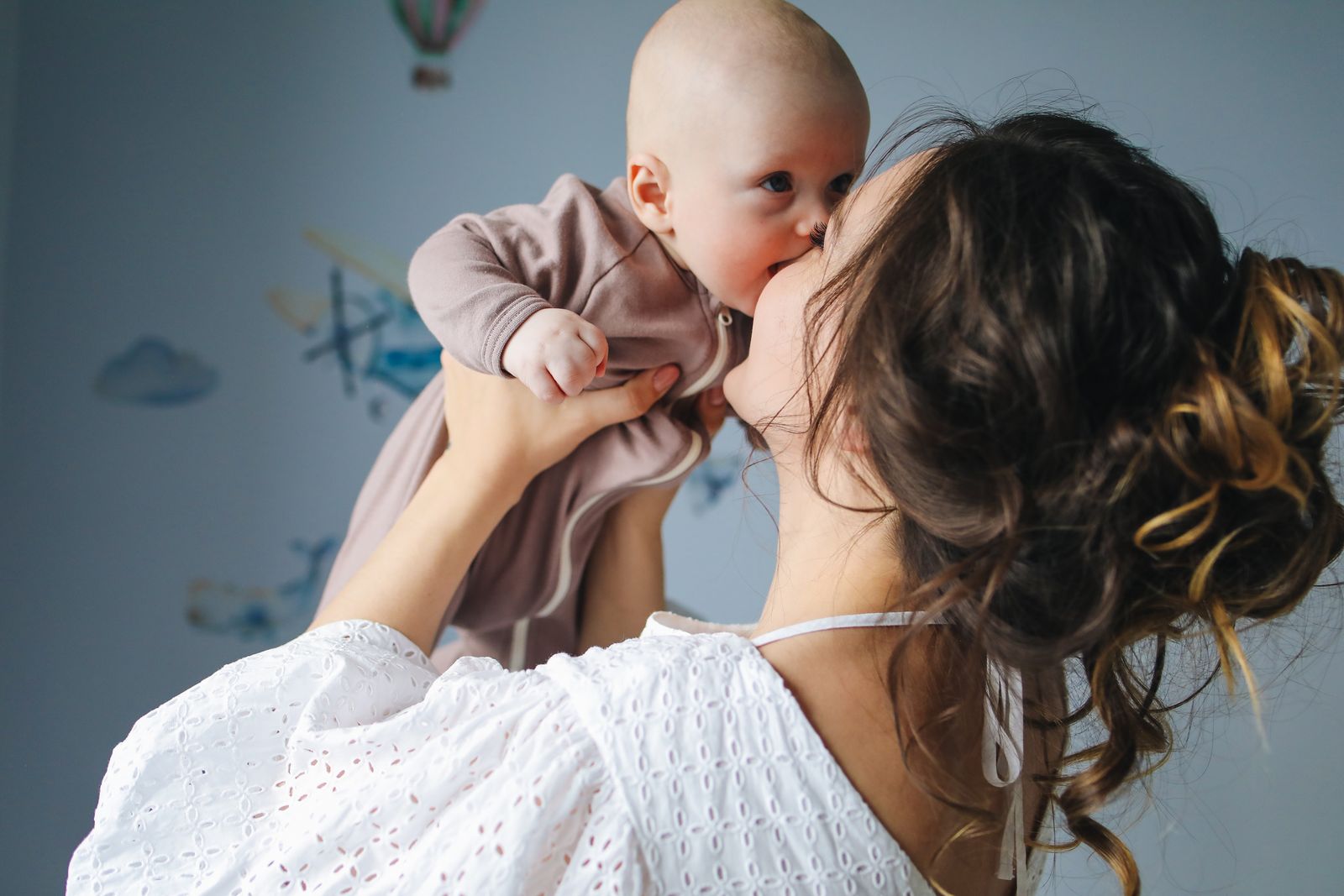 A mother holding her baby close and kissing their cheek